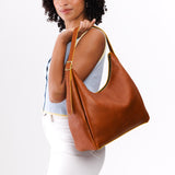 Sienna Large | Model holding u-shaped, flat-bottomed leather shoulder bag with adjustable strap