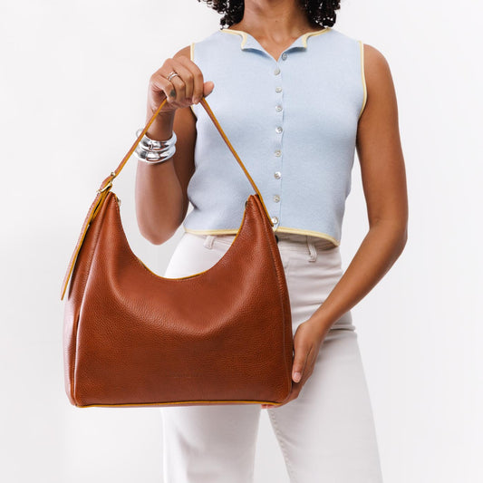 Sienna*Large | Model holding u-shaped, flat-bottomed leather shoulder bag with adjustable strap