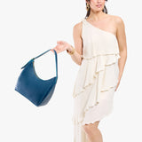 Caspian Medium | Model holding u-shaped, flat-bottomed leather shoulder bag with adjustable strap
