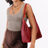 Chili Red Medium | Model holding u-shaped, flat-bottomed leather shoulder bag with adjustable strap