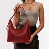 Chili Red Medium | Model holding u-shaped, flat-bottomed leather shoulder bag with adjustable strap