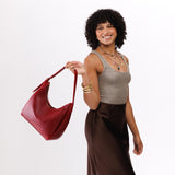Chili Red Medium | Model holding u-shaped, flat-bottomed leather shoulder bag with adjustable strap