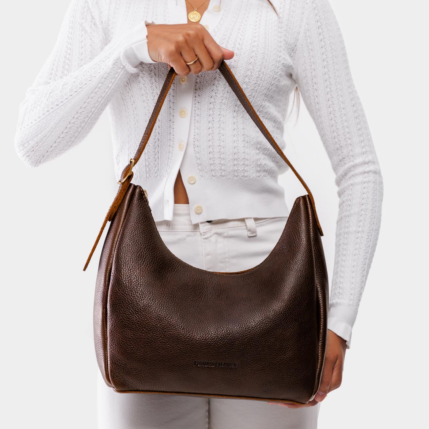 Coldbrew*Medium | Model holding u-shaped, flat-bottomed leather shoulder bag with adjustable strap