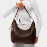 Coldbrew Medium | Model holding u-shaped, flat-bottomed leather shoulder bag with adjustable strap