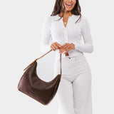 Coldbrew Medium | Model holding u-shaped, flat-bottomed leather shoulder bag with adjustable strap