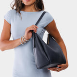 Night Owl Medium | Model holding u-shaped, flat-bottomed leather shoulder bag with adjustable strap