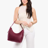 Orchid Medium | Model holding u-shaped, flat-bottomed leather shoulder bag with adjustable strap
