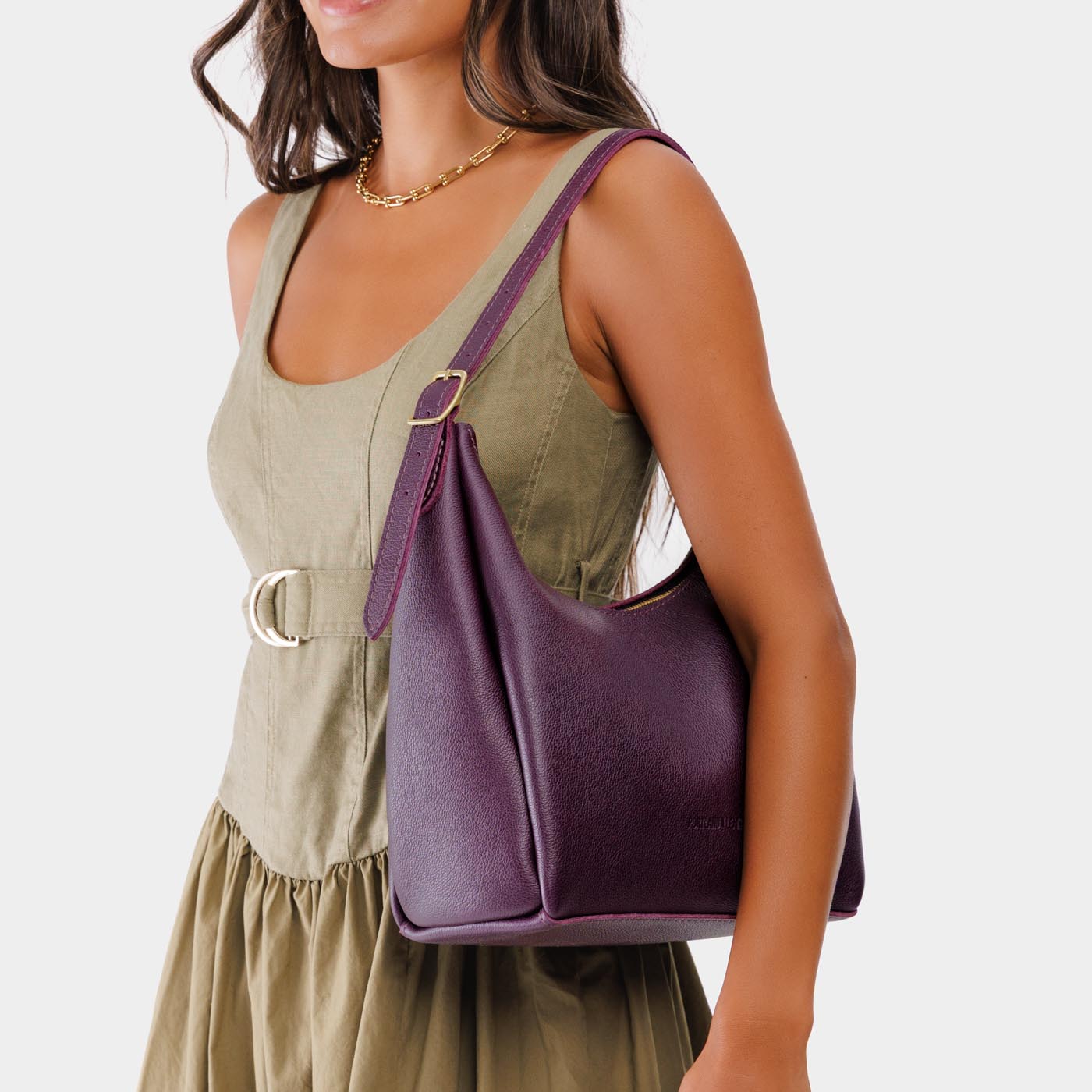 Plum*Medium | Model holding u-shaped, flat-bottomed leather shoulder bag with adjustable strap