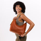 Sienna Medium | Model holding u-shaped, flat-bottomed leather shoulder bag with adjustable strap