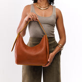 Sienna Medium | Model holding u-shaped, flat-bottomed leather shoulder bag with adjustable strap