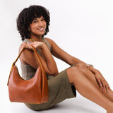 Sienna Medium | Model holding u-shaped, flat-bottomed leather shoulder bag with adjustable strap