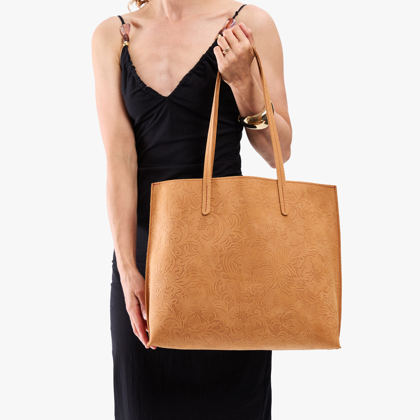Desert Flower | Model holding golden tote bag with debossed floral design