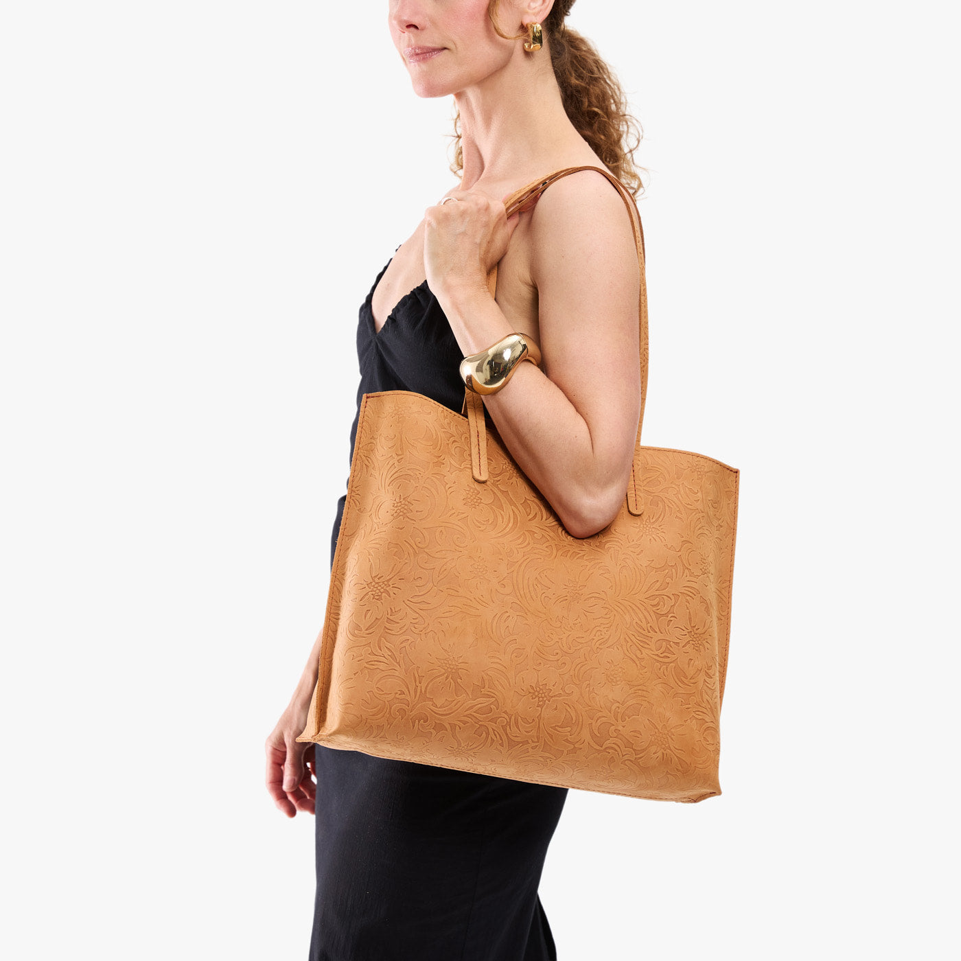 Desert Flower | Model holding golden tote bag with debossed floral design