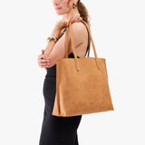 Desert Flower | Model holding golden tote bag with debossed floral design