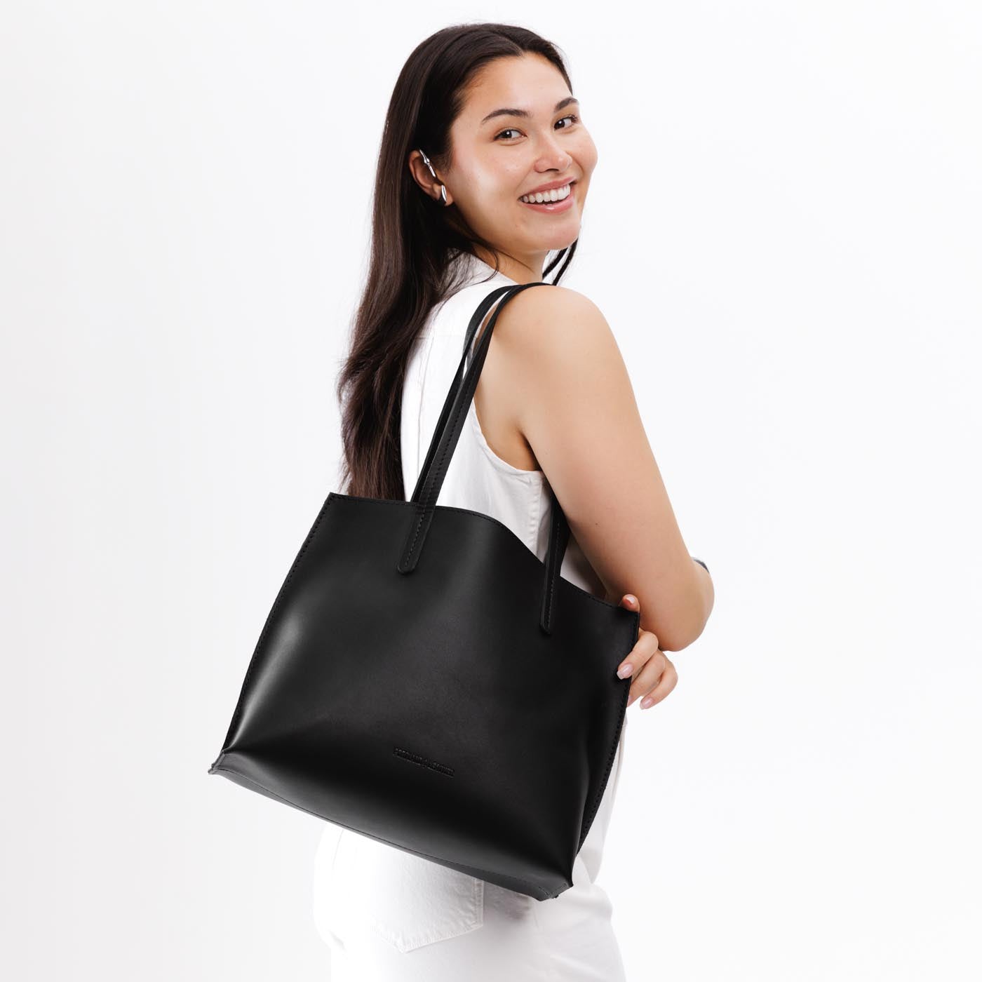 Black*Medium | Model holding leather tote bag with interior snap key loop