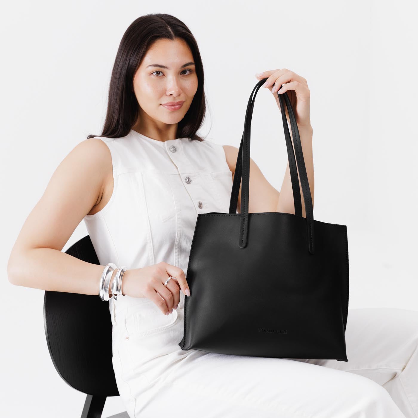 Black*Medium | Model holding leather tote bag with interior snap key loop