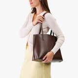 Chocolate Brown Medium | Model holding leather tote bag with interior snap key loop