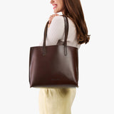 Chocolate Brown Medium | Model holding leather tote bag with interior snap key loop