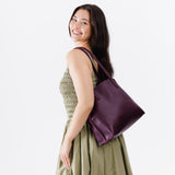 Plum Medium | Model holding leather tote bag with interior snap key loop