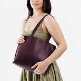 Plum Medium | Model holding leather tote bag with interior snap key loop