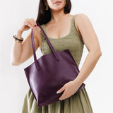 Plum Medium | Model holding leather tote bag with interior snap key loop
