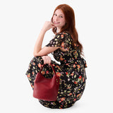 Chili Red Large | Model holding symmetrical bucket bag with handle, latch closure, and removable crossbody strap