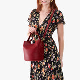 Chili Red Large | Model holding symmetrical bucket bag with handle, latch closure, and removable crossbody strap