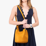 Sunshine Large | Model wearing symmetrical bucket bag with handle, latch closure, and removable crossbody strap
