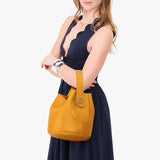 Sunshine Large | Model carrying symmetrical bucket bag with handle, latch closure, and removable crossbody strap