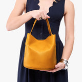 Sunshine Large | Model holding symmetrical bucket bag with handle, latch closure, and removable crossbody strap