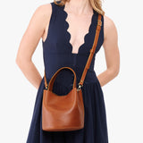 Honey Small | Model wearing symmetrical bucket bag with handle, latch closure, and removable crossbody strap