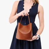 Honey Small | Model holding symmetrical bucket bag with handle, latch closure, and removable crossbody strap