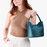 Westward Blue Small | Model holding symmetrical bucket bag with handle, latch closure, and removable crossbody strap