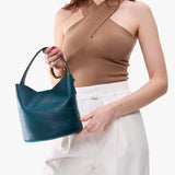 Westward Blue Small | Model holding symmetrical bucket bag with handle, latch closure, and removable crossbody strap