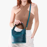 Westward Blue Small | Model holding symmetrical bucket bag with handle, latch closure, and removable crossbody strap