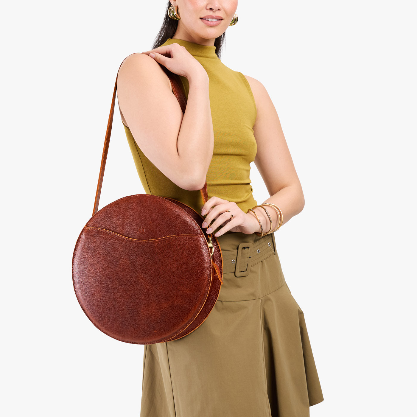 Nutmeg | Model carrying large circle shaped leather bag with top zipper and carrying strap