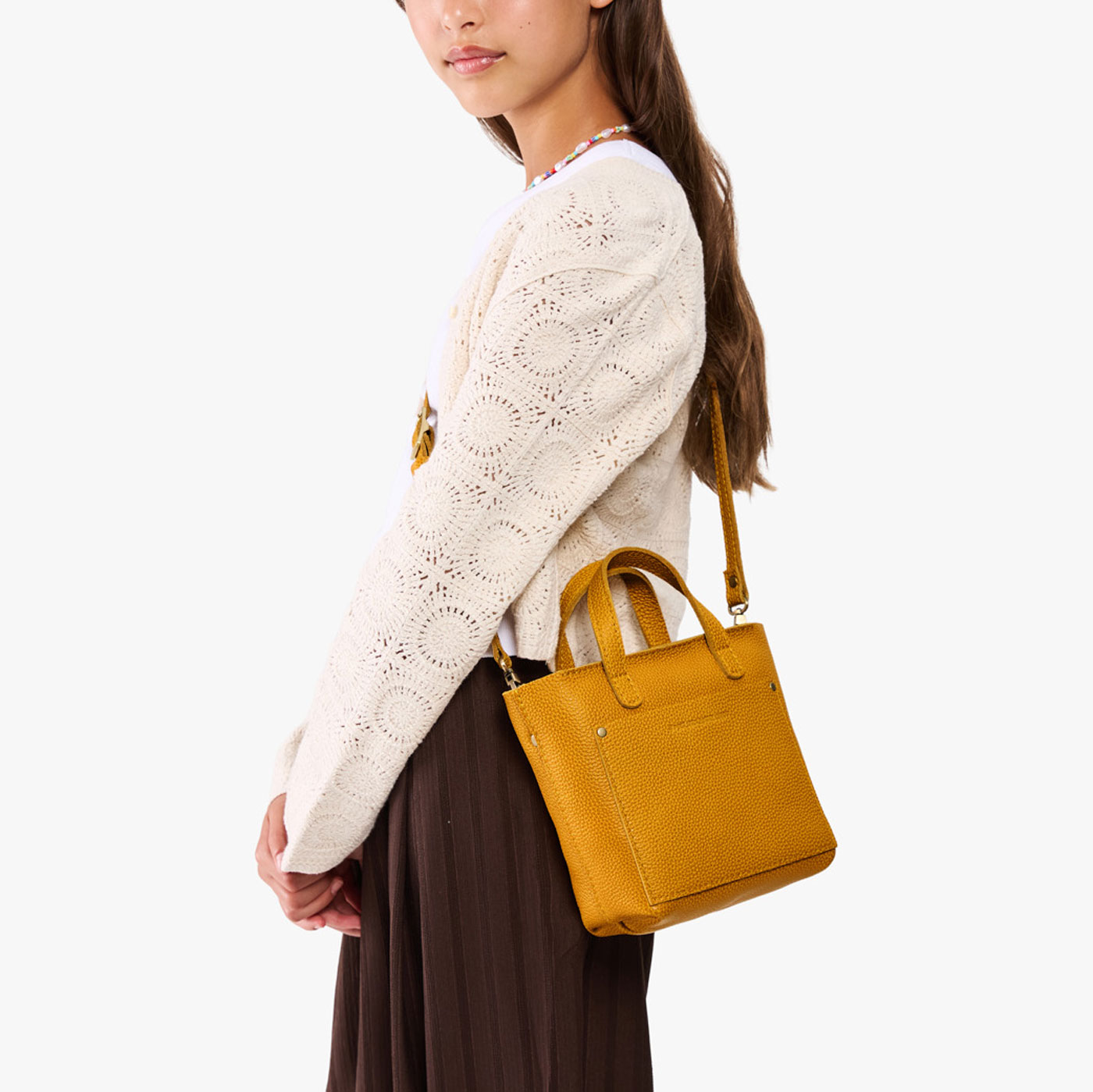 Sunshine | A young model wearing a petite crossbody tote bag with zipper closure and front pocket