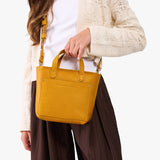 Sunshine | A young model wearing a petite crossbody tote bag with zipper closure and front pocket