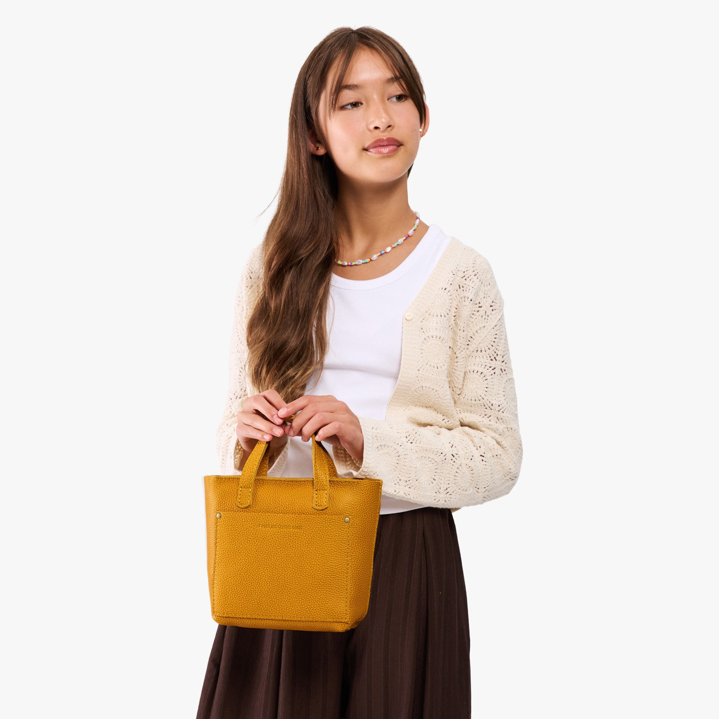 Sunshine | A young model wearing a petite crossbody tote bag with zipper closure and front pocket