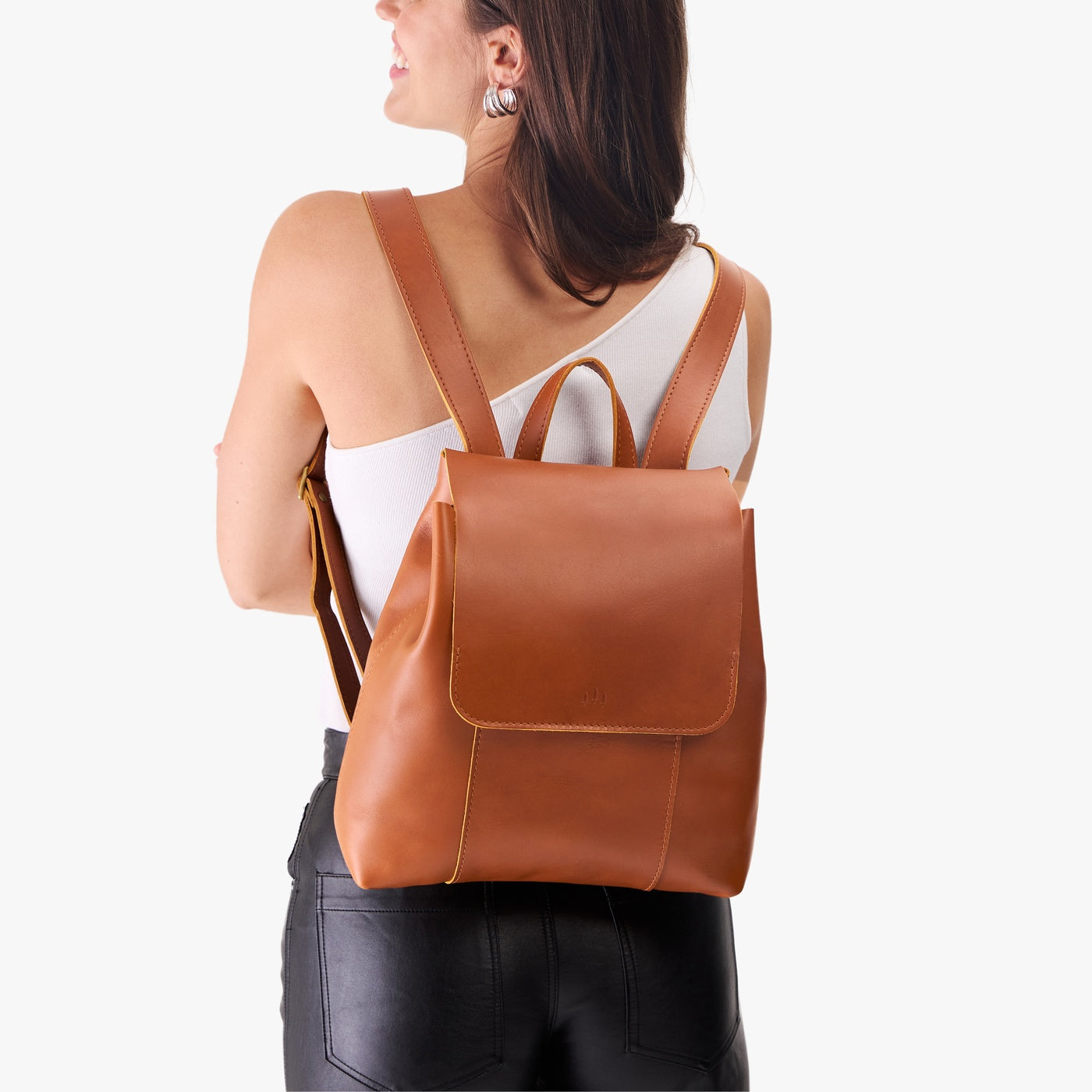 Honey | Model wearing a leather backpack on a white background