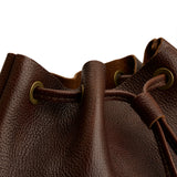 Coldbrew | Close-up of a brown leather drawstring backpack with grommets.