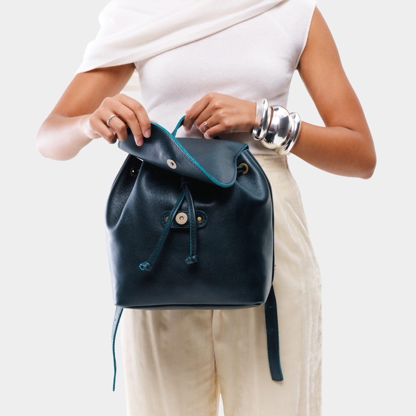 Boreal | Dark blue leather drawstring backpack being held by a person wearing a white shirt.