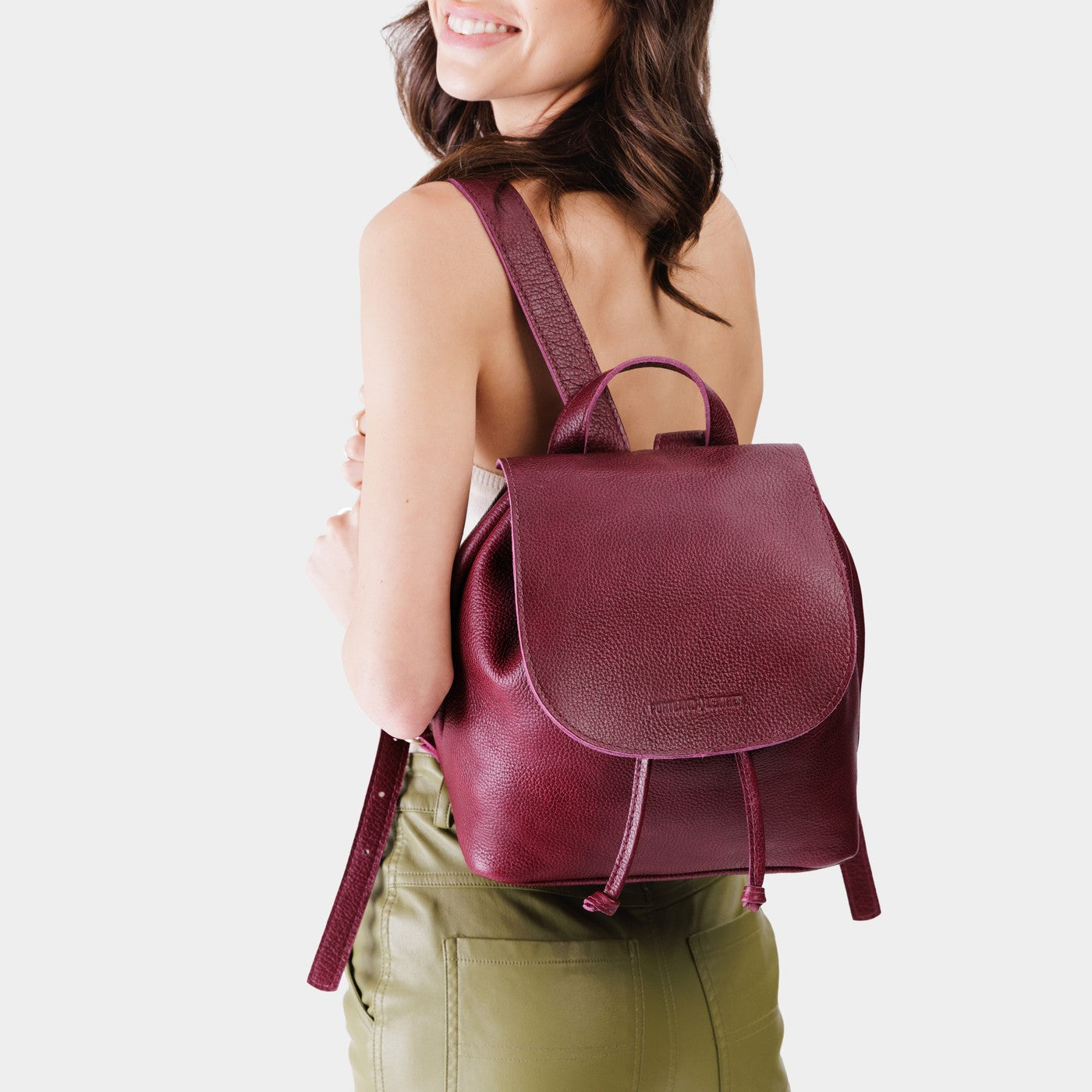 Orchid | Pebbled burgundy leather drawstring backpack being worn by a person.