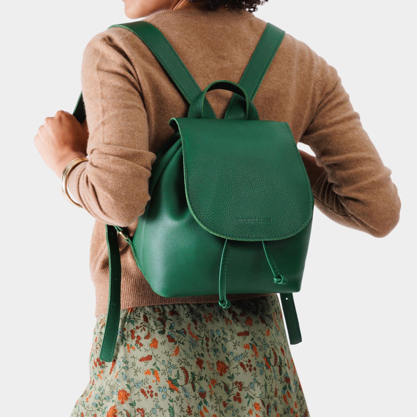 Bacalar | Pebbled green leather drawstring backpack being worn by a person wearing a brown sweater.