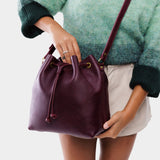 Plum Large | Model holding slouchy crossbody bag with drawstring closure