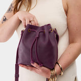 Plum Small | Model holding slouchy crossbody bag with drawstring closure