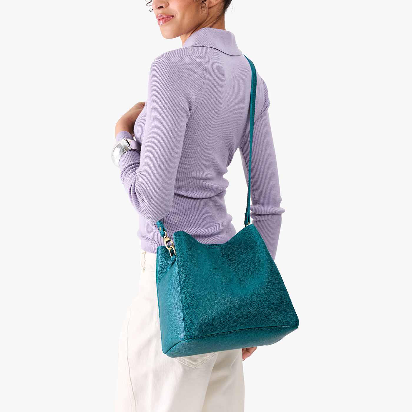 Aquarius | Model wearing symmetrical bucket bag with latch closure and removable crossbody strap