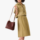 Cognac | Model wearing symmetrical bucket bag with latch closure and removable crossbody strap