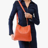 Koi | Model wearing symmetrical bucket bag with latch closure and removable crossbody strap