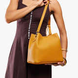 Sunshine | Model wearing a symmetrical bucket bag with latch closure and removable crossbody strap
